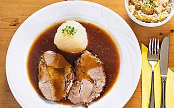 Schweinsbraten mit Erdäpfel-Knödeln und Speck-Sauerkraut - (c) Foto: Eisenhut & Mayer Schweinsbraten